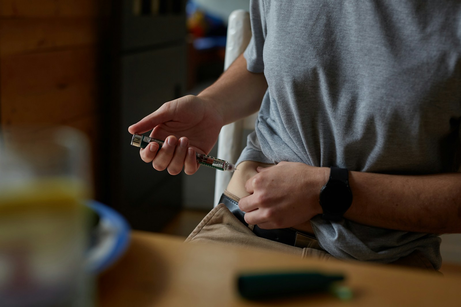 Person administering a subcutaneous injection into their abdomen at home